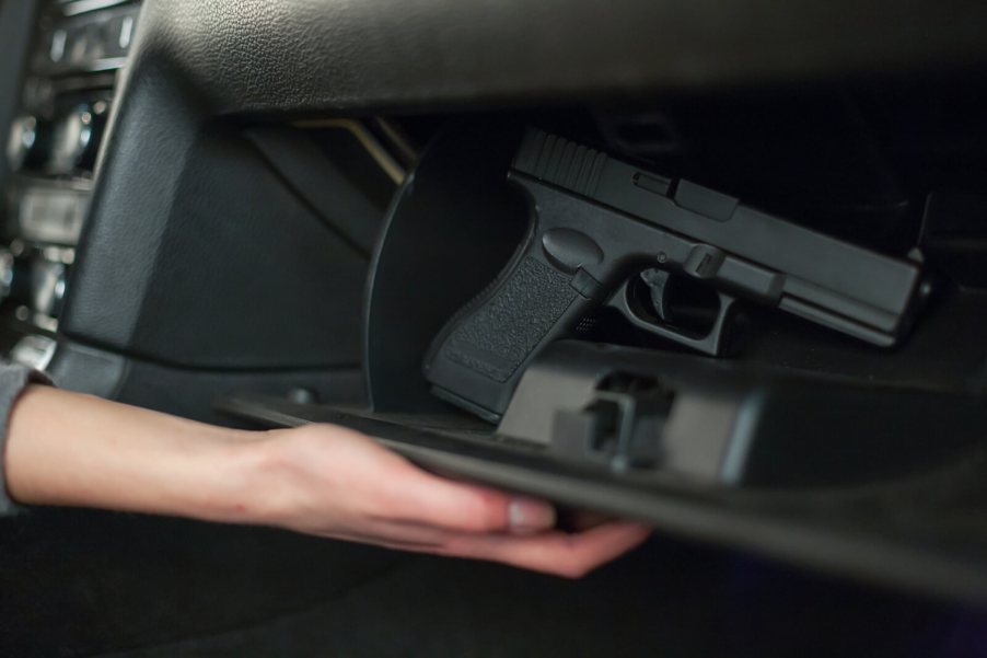 A driver reaches for a concealed handgun in a glovebox.