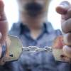 A car thief in handcuffs after police officers pulled him out of a stolen car.