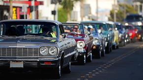 A car cruise with lowrider and classic car builds on city streets.