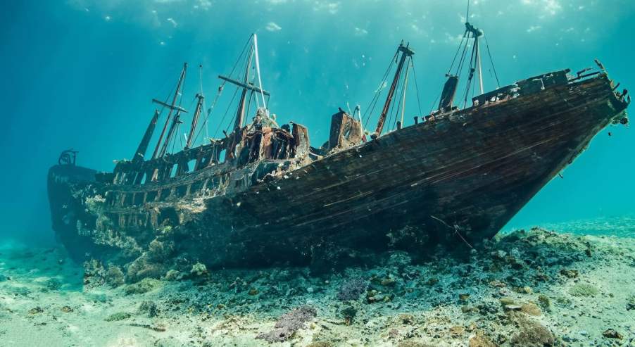 Old shipwreck at the bottom of a brilliant, blue ocean.