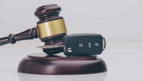 Car key fob resting sideways on gavel block as a depiction of how certain traffic violations can immediately suspended your driver's license