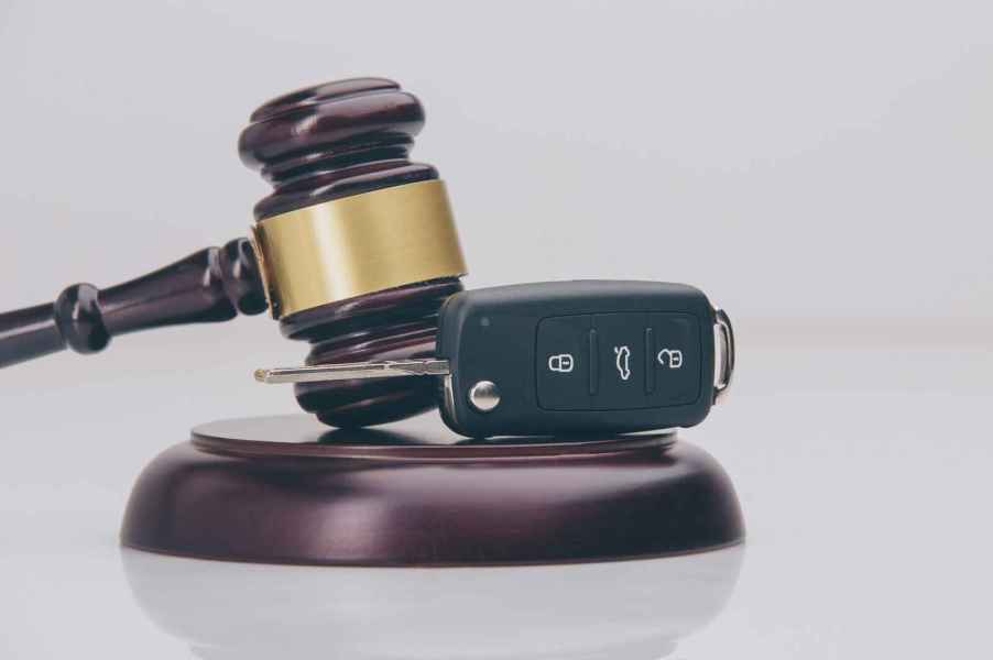 Car key fob resting sideways on gavel block as a depiction of how certain traffic violations can immediately suspended your driver's license