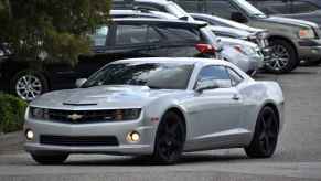 A charcoal Chevrolet Camaro two-door coupe sports car in a parking lot with fog lights illumunated