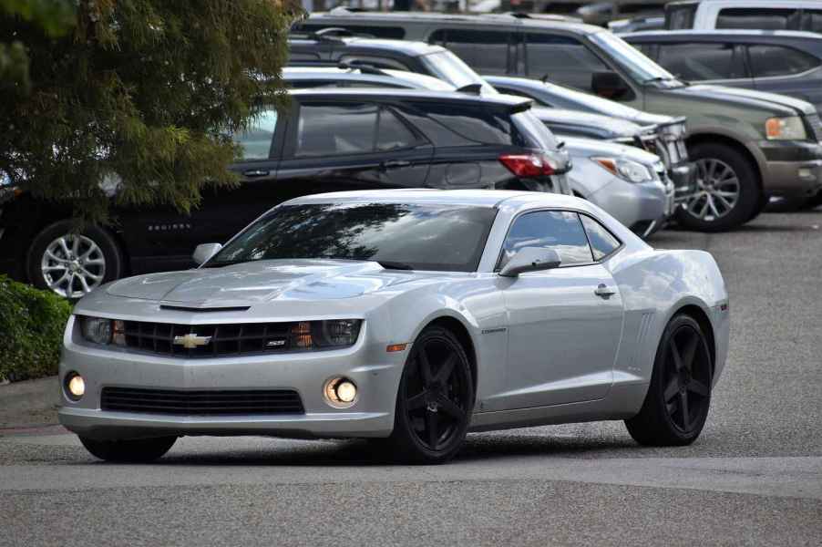 A charcoal Chevrolet Camaro two-door coupe sports car in a parking lot with fog lights illumunated