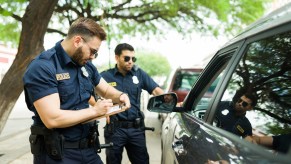 Two police officers writing a ticket at a traffic stop