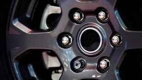 A car wheel rim with lug nuts in close view one is a locking lug nut that requires a wheel lock key