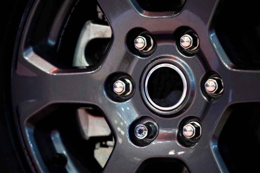 A car wheel rim with lug nuts in close view one is a locking lug nut that requires a wheel lock key